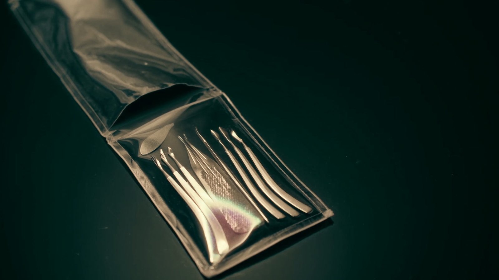 A sealed pouch of steel nail tools, opened on a dark salon table