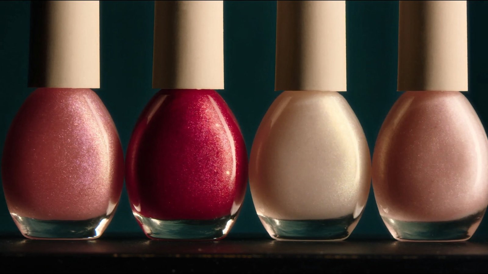 A row of rose and pearl lacquer bottles catching the light